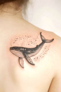 a whale tattoo on the back of a woman's shoulder