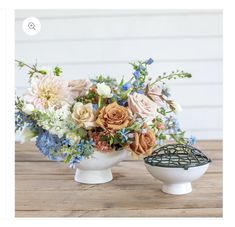 a vase with flowers in it sitting on a table next to an object that looks like a birdcage