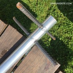 a metal object sitting on top of a wooden table next to green grass and bushes