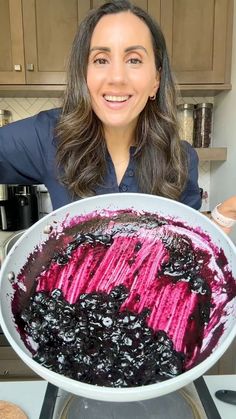 a woman holding up a large bowl of blueberries