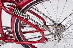 the front wheel of a red bicycle with chrome spokes