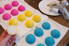 a person is holding some kind of doughnuts on a napkin with colored sprinkles