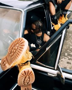 two people sitting in the driver's seat of a car with their feet up