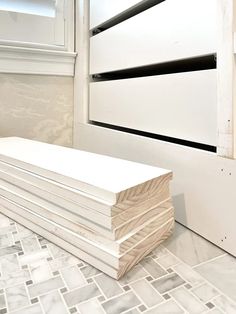 a stack of white plywood boards sitting on top of a tiled floor