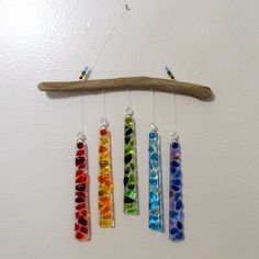 a wind chime hanging from a wall with four different colored glass beads on it