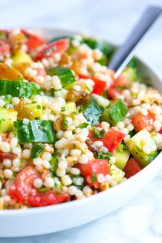 a white bowl filled with couscous and veggies on top of a table