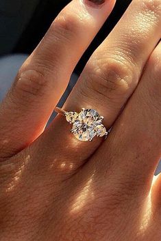 a woman's hand with a diamond ring on top of her finger and an engagement band