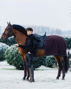 a man standing next to a horse in the snow