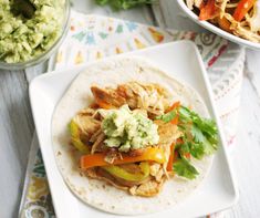 a tortilla with chicken, peppers and guacamole is on a plate