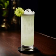 a tall glass filled with limeade on top of a wooden table