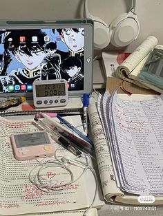 an open laptop computer sitting on top of a desk next to books and headphones