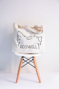 a white tote bag sitting on top of a wooden chair