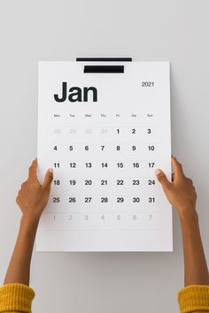 someone holding up a calendar with the word jan on it