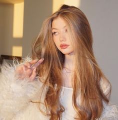 a woman with long hair is holding her finger up to the side as she stands in front of a mirror