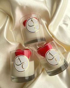 three glass candles sitting on top of a white cloth