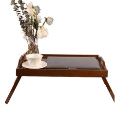 a tray with flowers and a cup on it sitting on top of a wooden table