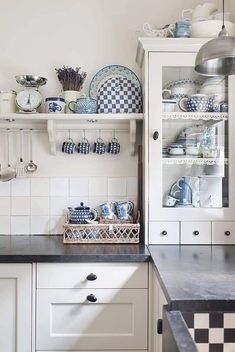 a kitchen filled with lots of white and blue dishes on top of shelves next to a counter