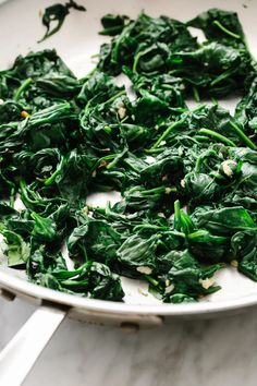 spinach leaves are being cooked in a pan