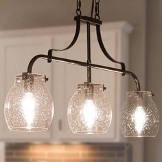 three lights hanging from the ceiling in a kitchen