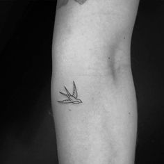 a black and white photo of a person's arm with a bird tattoo on it