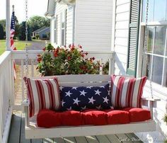 a white porch swing with red, white and blue pillows