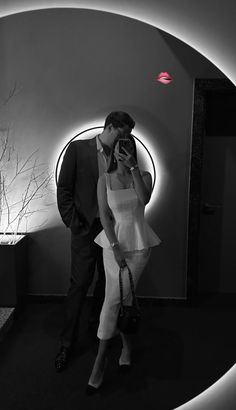 a man and woman standing in front of a wall with a circular light on it