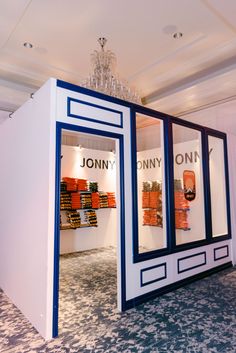 a display case in the middle of a room with orange boxes on it and chandelier hanging from the ceiling