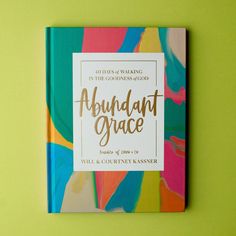 the book abundant grace is sitting on top of a green table next to a yellow wall