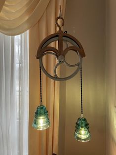 two lights hanging from the ceiling in a room with curtains and drapes on the windowsill