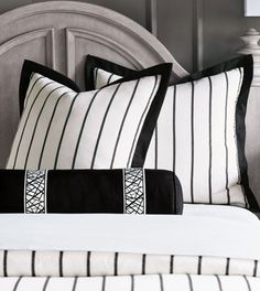 two black and white pillows sitting on top of a bed next to a headboard