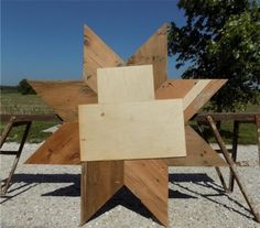 a wooden star sculpture sitting on top of a gravel field