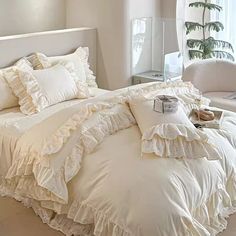 a white bed with ruffled sheets and pillows