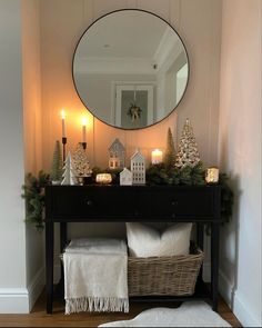 a table with candles and decorations on it in front of a round mirror over a black dresser