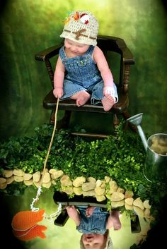 a baby sitting in a chair on top of a table with fish and plants around it