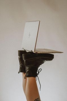 a woman's legs with black leather boots and her laptop on top of her head