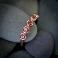 Oregon Sunstone and 14k Rose Gold Multistone Ring, 3mm x 5 Stone design, Oregon Sunstone Anniversary Band, Gold Gemstone Ring This beautiful ring features five 3mm Oregon Sunstones set in our hand carved 14k Rose Gold Setting. Each stone is unique, featuring bits of schiller that sparkle and glow. Each ring features 5 unique stones that will vary in amount of schiller and slight color variation as each ring is a One of a Kind piece. Thank you! Rose Gold Stackable Rings With Bezel Setting, Rose Gold Stackable Sapphire Ring, Rose Gold Stackable Rings With Gemstone, Round Cut, Stackable Rose Gold Sapphire Ring, Rose Gold Gemstone Stackable Anniversary Rings, Rose Gold Gemstone Stackable Rings, Rose Gold Stackable Rings With Gemstones, Stackable Rose Gold Birthstone Ring With Round Band, Rose Gold Stackable Rings With Birthstone