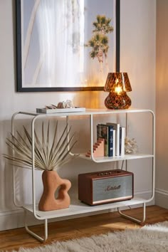 a white shelf with a lamp and some books