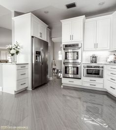 a large kitchen with white cabinets and stainless steel appliances in the center, along with marble flooring