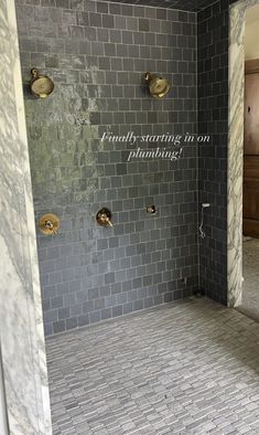 a bathroom with grey tile and gold fixtures on the shower wall that says, perfectly starting on plumbing