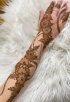 a woman's hand with henna tattoos on top of white furnishing