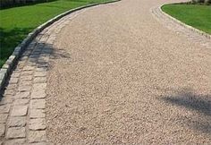 a paved road with trees and grass in the background