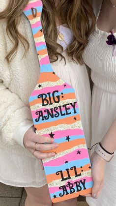 two women holding up a wooden sign that says,'big ansleyy '