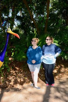 two women are standing next to a fake bird