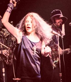 a woman with long hair standing in front of microphones and singing into a mic