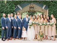 a group of people standing next to each other in front of a gazebo with flowers and greenery