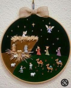 a christmas ornament hanging on a wall with nativity scene in the background