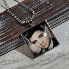 a necklace with an image of elvis presley on it sitting on a wooden surface next to a chain