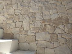 a stone wall with steps leading up to it and sunlight coming through the window onto the floor