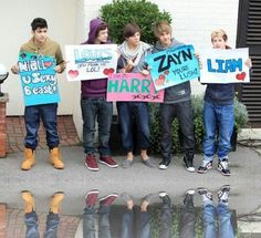 several people holding signs in front of a house