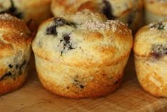 blueberry muffins sitting on top of a wooden cutting board